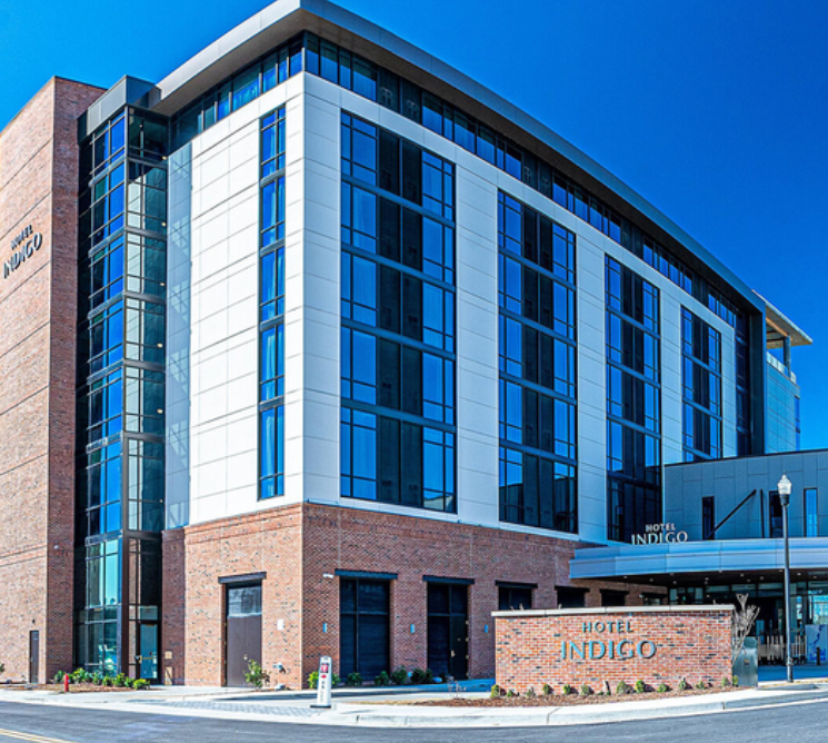 An outside image of Hotel Indigo. The exterior has bricks and large windows with an overall new and modern feel.